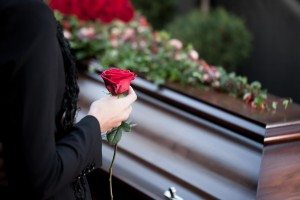 Woman placing flower on a coffin