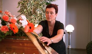 woman checks flowers on a casket
