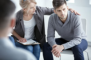 A grieving man being consoled by a social worker